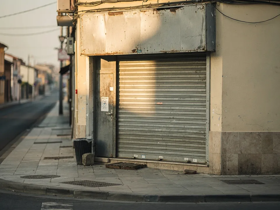 Devanture de commerce de quartier au petit matin, volets fermés, rue calme, illustrant les clients qui passent devant un site invisible
